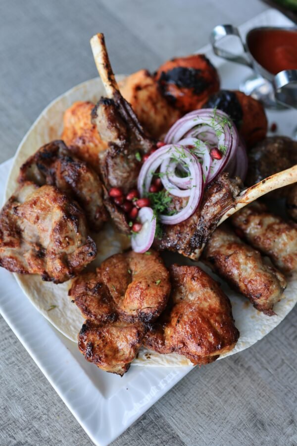 A mouthwatering assortment of grilled meats, served with onions and sauces. Perfect for dinner.