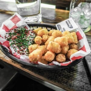 Golden tater tots served with dipping sauce in a casual dining setting.