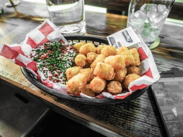 Golden tater tots served with dipping sauce in a casual dining setting.